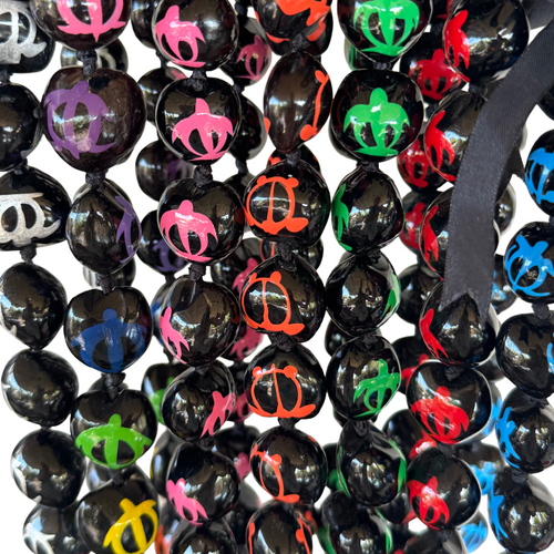 Black kukui nut beads with colorful turtles on a white background