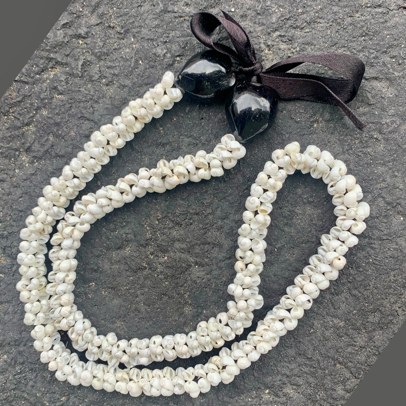 Mongo shell necklace with black pendant on a textured surface