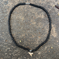 Black beaded necklace with a pendant on a textured surface