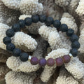 Black and purple beaded bracelet on a textured beige surface