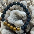 Black and gold beaded bracelet on a textured white surface