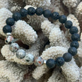 Black and gray beaded bracelet on a textured coral background