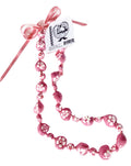 A black and pink kukui nut lei with a floral pattern and an adjustable black ribbon closure.
