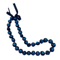 A black and blue kukui nut lei with a turtle pattern and an adjustable black ribbon closure.