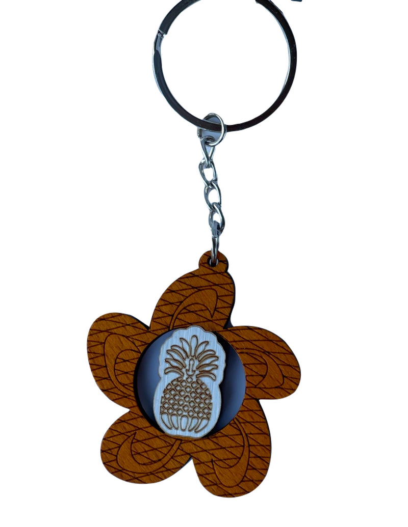 Wooden Hawaiian keychain featuring a plumeria blossom shape with a carved pineapple center design, lightweight and tropical style.