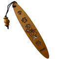 A collection of wooden bookmarks with Hawaiian inspired designs, featuring phrases and images related to Hawaii, displayed on a surface with a floral patterned book in the background.