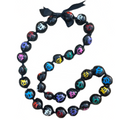 A black and multicolored kukui nut lei with a turtle pattern and an adjustable black ribbon closure.