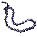 A black and purple kukui nut lei with a turtle pattern and an adjustable black ribbon closure.